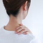 後ろ姿で首の後ろを手で押さえる女性