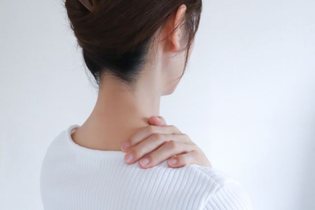 後ろ姿で首の後ろを手で押さえる女性