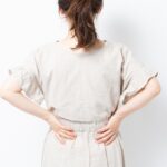 柏市・増尾で腰痛に悩む方のイメージ（腰に手を当てる女性）