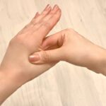 手の甲のツボを親指で押す手元
