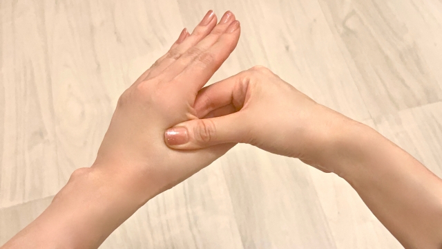 手の甲のツボを親指で押す手元