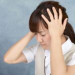 両手で頭を押さえてうつむく女性