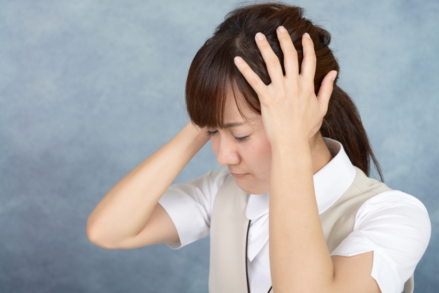 両手で頭を押さえてうつむく女性