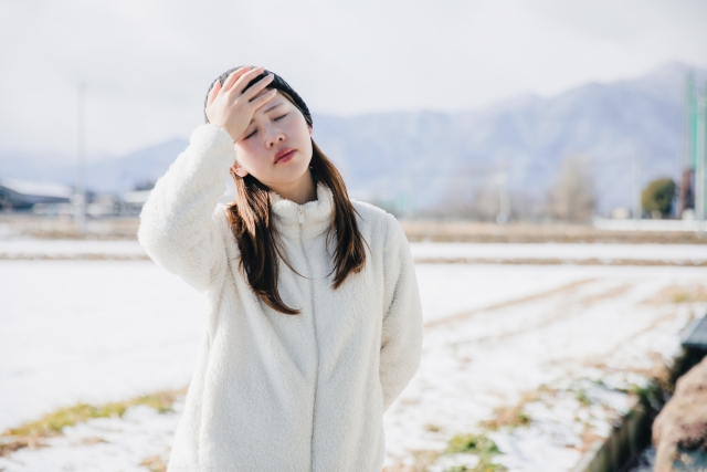 屋外で額に手を当てる女性